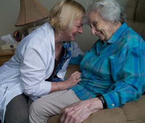 A nurse shares a laugh and a hug with her elderly female patient.